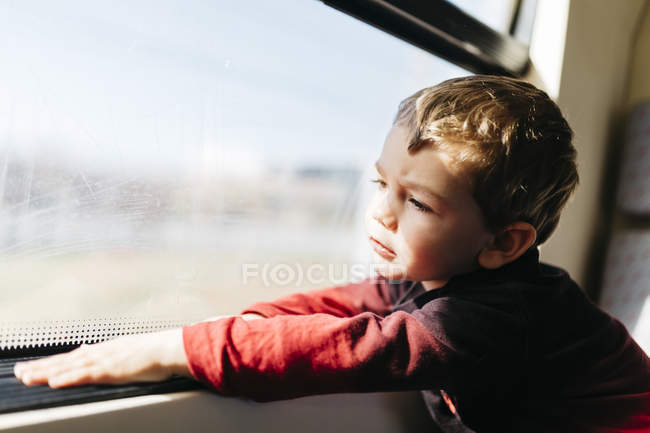 Ritratto di bambino nel suo primo viaggio in treno guardando attraverso il finestrino — Foto stock