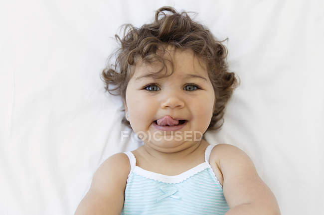 Baby Girl Lying On White Bedsheet Brown Hair Curly Hair Stock