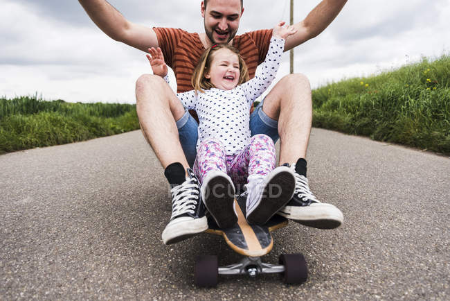 Figlia e padre seduti sullo skateboard — Foto stock
