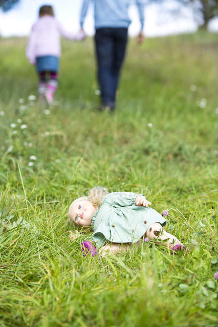 Poupée couchée sur la prairie tandis que l'homme s'en va avec la petite fille — Photo de stock