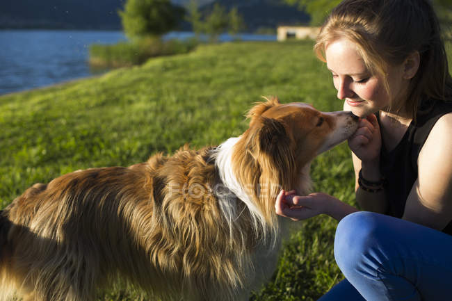 Adolescente con il suo cane sulla riva del lago — Foto stock