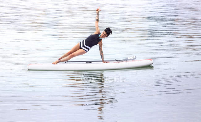 Woman practicing paddle board yoga — Yoga Pose, sea - Stock Photo ...