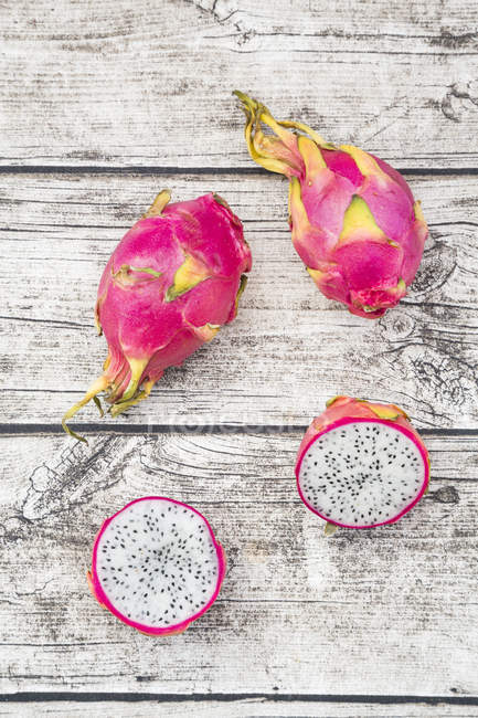 Halved and whole dragon fruits — Stock Photo