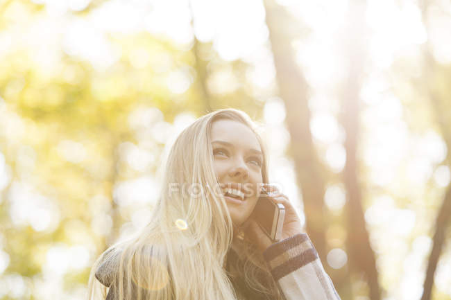Smiling teenage girl on cell phone in autumn — Stock Photo