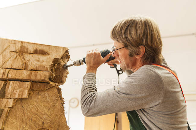 Wood carver in workshop working on sculpture with milling machine — Stock Photo