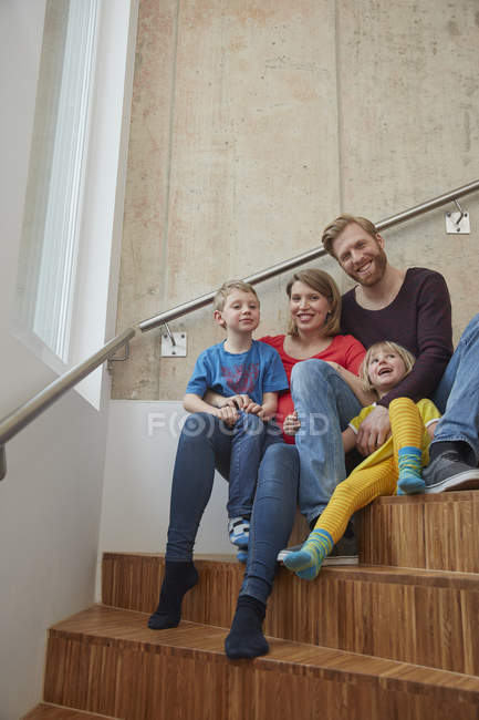 Портрет улыбающейся семьи, сидящей на лестнице — стоковое фото