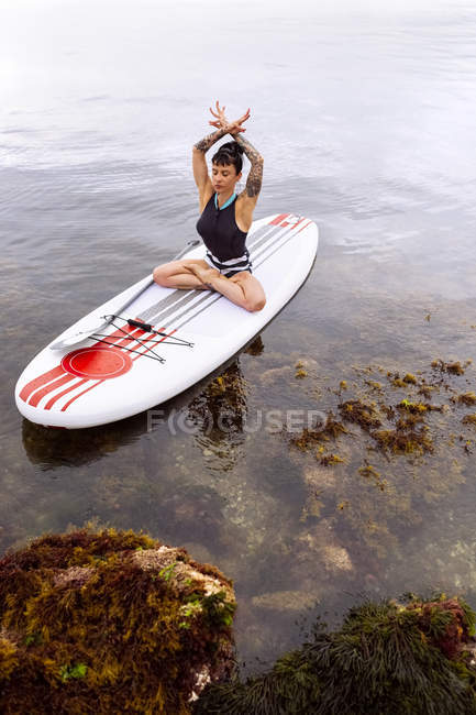 Woman practicing paddle board yoga — Stock Photo