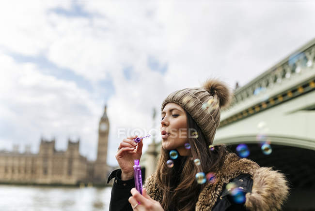 Uk, london, junge frau pustet seifenblasen vor big ben — Stockfoto