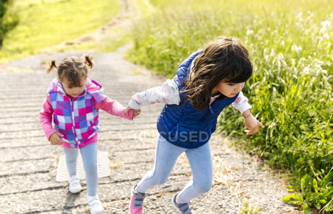 Duas irmãs caminhando de mãos dadas em um caminho — Fotografia de Stock