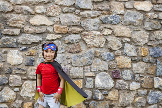 Pequeno grande herói com uma máscara contra uma parede de pedra — Fotografia de Stock