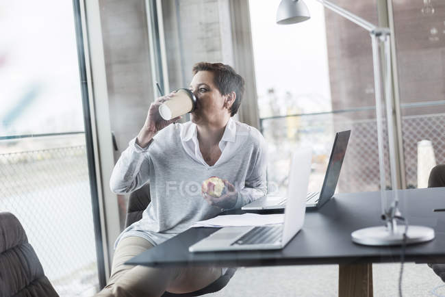 Empresaria en oficina bebiendo café - foto de stock