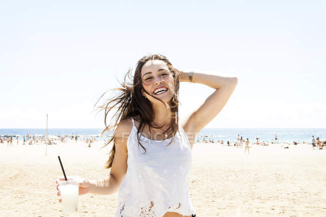 Jeune femme buvant un cocktail sur la plage — Photo de stock