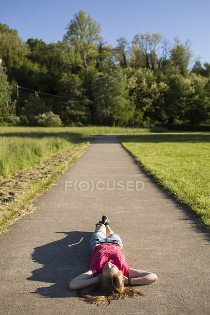 Teenage girl ying on a path in the middle of nature — Stock Photo