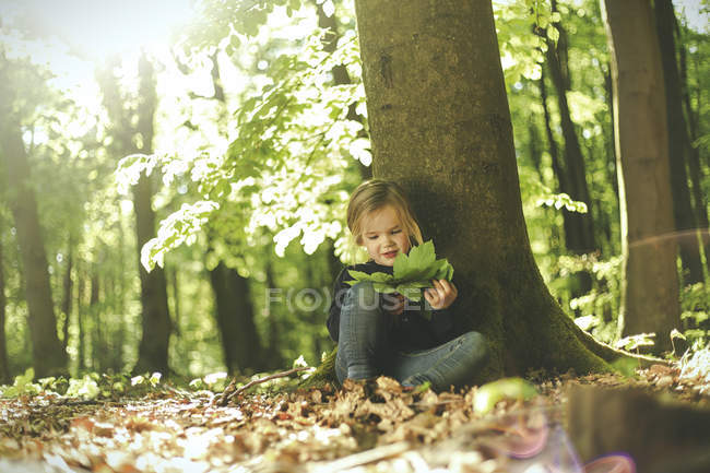 Menina na floresta examinando folhas — Fotografia de Stock