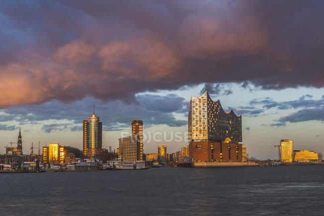 Alemania, Hamburgo, Hafencity con el Salón Filarmónico del Elba al atardecer nublado - foto de stock