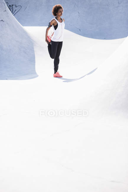 Junge Frau dehnt sich im Skatepark — Stockfoto
