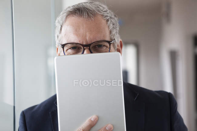 Hombre de negocios exitoso parado en su oficina sosteniendo tableta digital - foto de stock