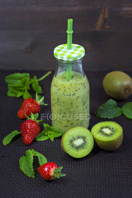 Glass bottle of kiwi lime smoothie on table — Ready To Eat, halves - Stock  Photo | #176844274