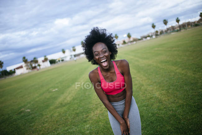 Laughing female athlete standing on field — Stock Photo