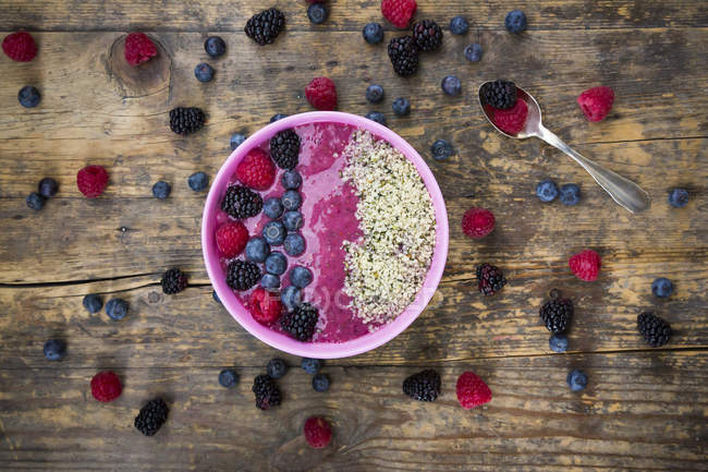 Bowl with fruit smoothie garnished with berries and hemp seeds — Stock Photo
