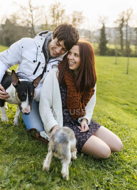 Casal jovem com seus cães em um prado — Fotografia de Stock