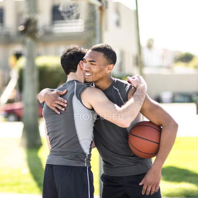 Dois jogadores de basquete abraçando na quadra ao ar livre — Fotografia de Stock