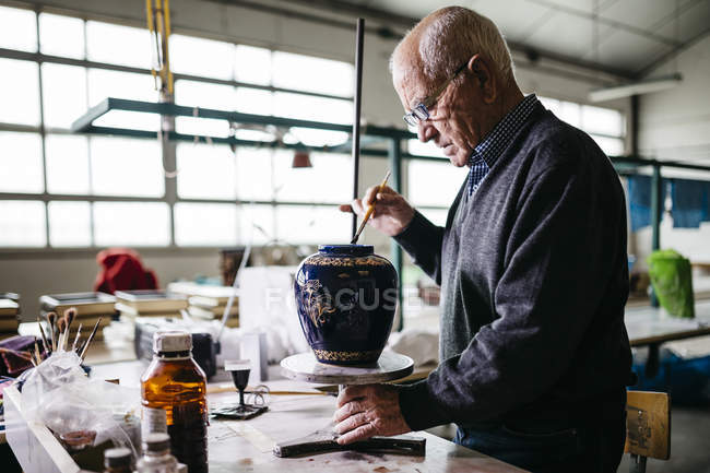 Homem sênior decorando vaso de cerâmica em seu tempo livre — Fotografia de Stock
