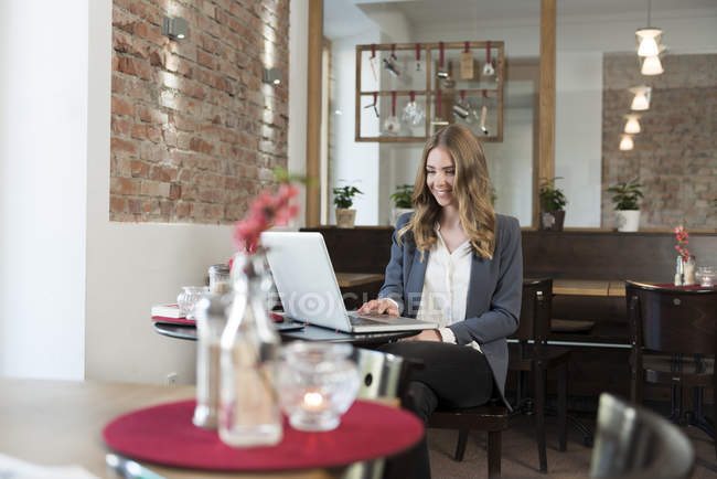 Junge Frau benutzt Laptop in einem Café — Stockfoto