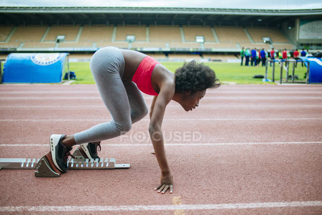 Jeune athlète noir se préparant pour la course dans le stade — Photo de stock