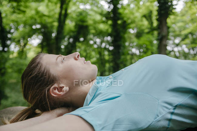 Jeune femme relaxante sur banc en forêt — Photo de stock