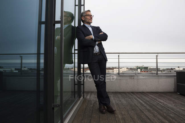 Erfolgreicher Geschäftsmann steht zufrieden auf Büroterrasse — Stockfoto