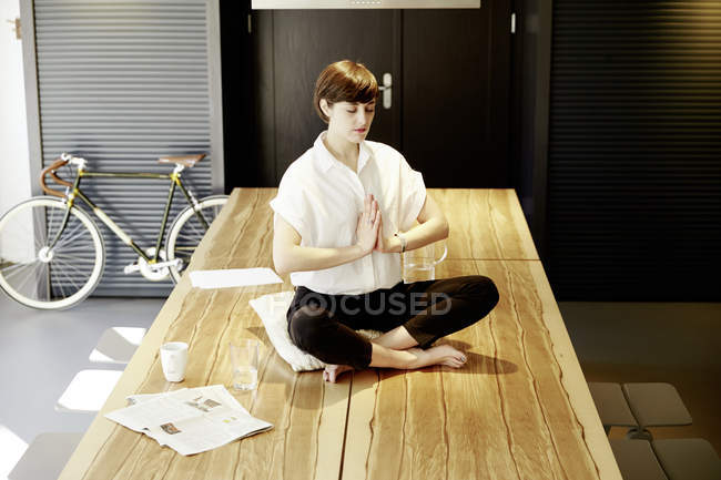 Mujer practicando yoga sobre mesa de madera - foto de stock
