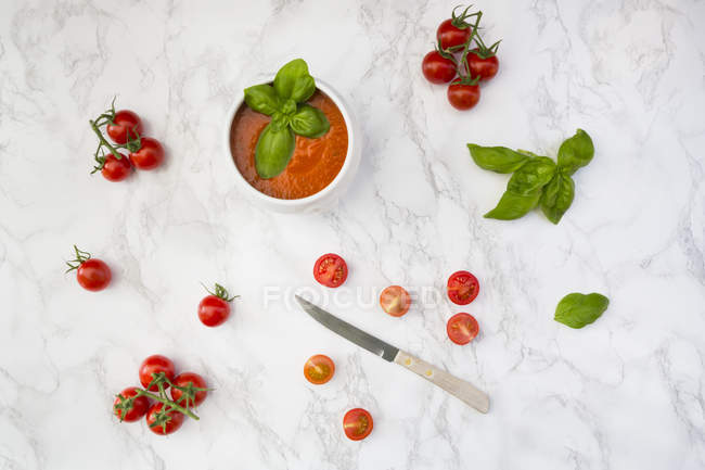 Sopa de tomate con tomate y cuchillo sobre mármol - foto de stock