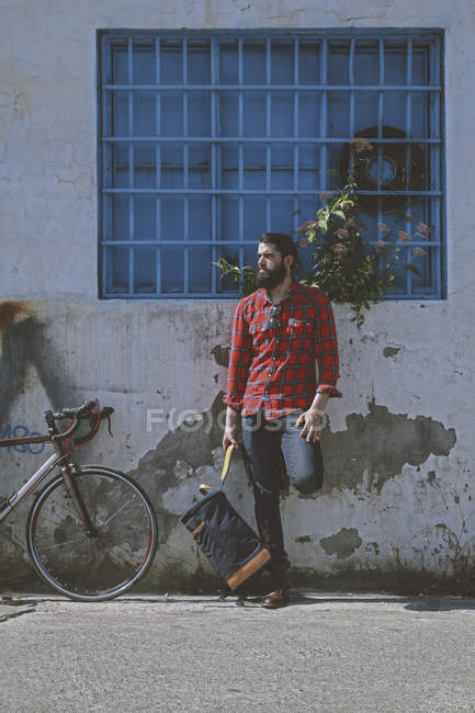 Man and racing cycle leaning against facade — Stock Photo