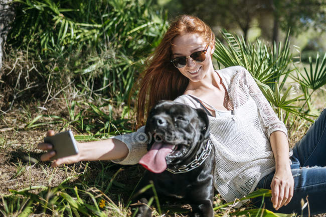 Sorrindo jovem mulher tomando uma selfie com seu cão — Fotografia de Stock