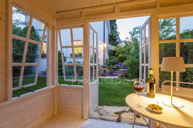 Rotweinglas und Flasche und Schale mit Oliven auf dem Tisch in einem Gartenhaus — Stockfoto