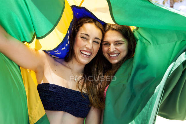 Dois amigos vestindo roupa de praia brincando com a bandeira brasileira — Fotografia de Stock