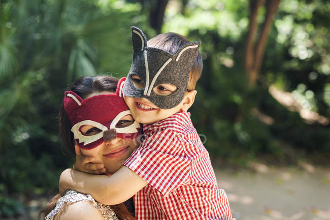 Mère et petit fils avec des masques d'animaux jouant dans le parc — Photo de stock