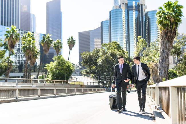 Dos hombres de negocios caminando con equipaje en la ciudad — Stock Photo