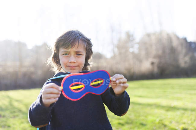 Retrato de un niño mostrando su máscara de superhéroe - foto de stock