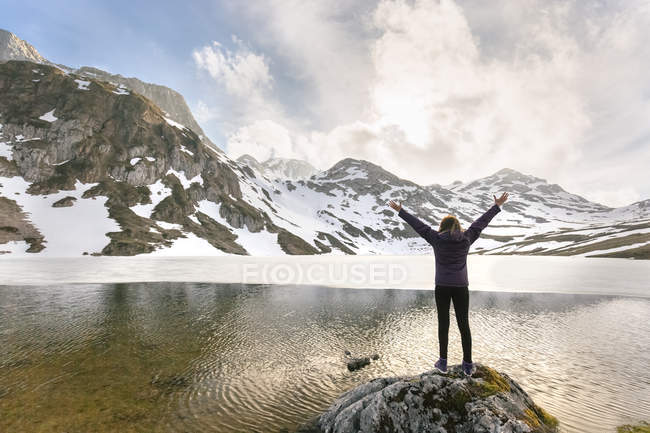 Donna in piedi con le braccia alzate al lago di montagna, Spagna, Asturie, Somiedo — Foto stock