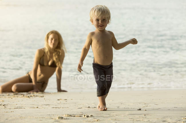 Thailandia, ragazzo felice sulla spiaggia con la madre sullo sfondo — Foto stock