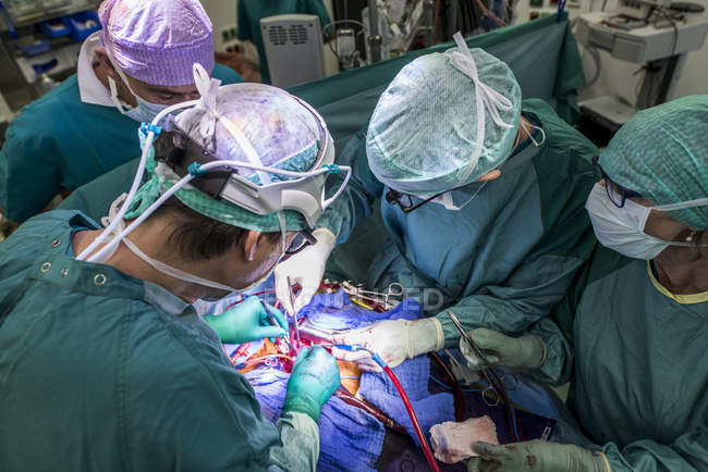 Cirujanos cardíacos y enfermeras de quirófano durante una operación - foto de stock