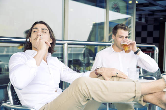 Два молодых человека курят и пьют пиво на круизном лайнере — стоковое фото
