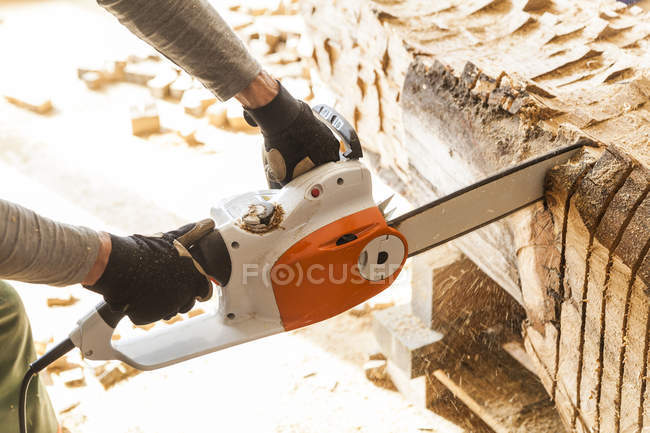 Sculpteur en bois en atelier travaillant sur bois avec une tronçonneuse — Photo de stock