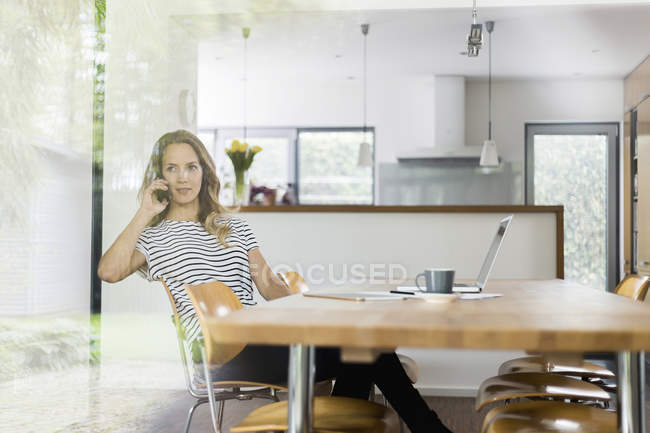 Frau am Handy sitzt am Tisch — Stockfoto