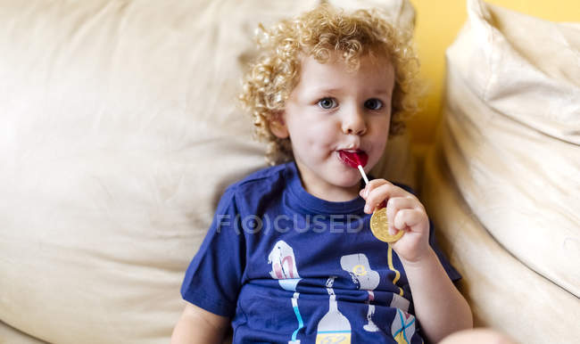 Ritratto di bambino con lecca-lecca seduto sul divano — Foto stock