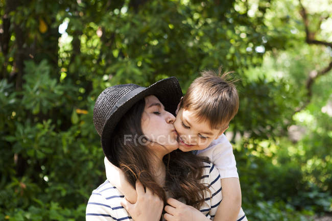 Мать целует сына на улице — стоковое фото
