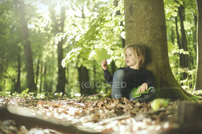 Menina na floresta examinando folhas — Fotografia de Stock
