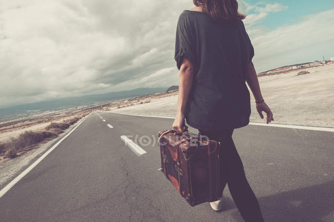 Giovane donna con valigia camminare su una strada — Foto stock